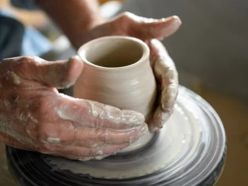Pottery Workshop experience shaping a clay pot on a spinning wheel with skilled hands.