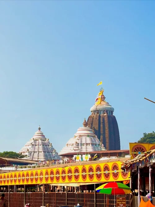 Jagannath Temple in Puri Odisha with iconic spire and colorful surroundings under clear blue sky featured in Odisha tour packages