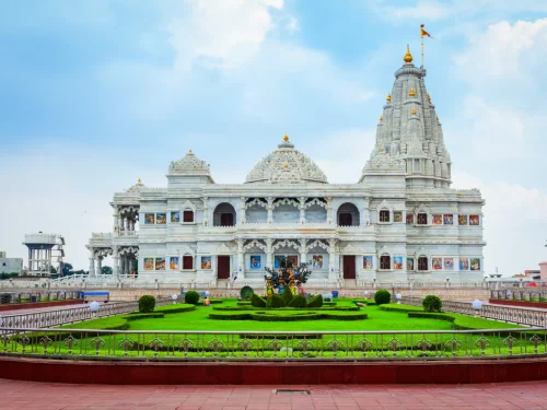 Prem Mandir at Vrindavan during clear daytime, featuring white marble architecture, golden spires, landscaped gardens, perfect spiritual experience with Mathura Vrindavan tour package.
