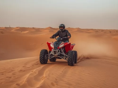 Quad Biking adventure riding a powerful ATV across golden desert sand dunes.