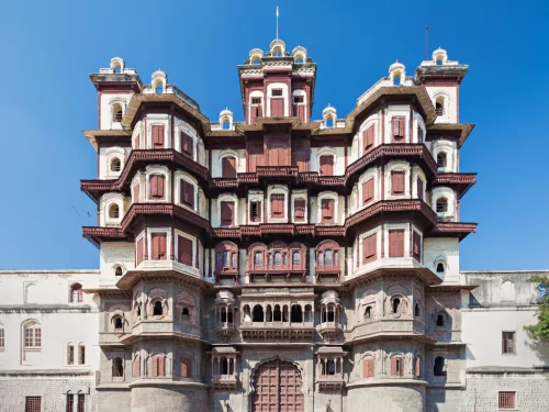 Rajwada Palace at Indore during clear daylight, featuring red-white Maratha arches balconies domes, perfect cultural experience Madhya Pradesh tour package.