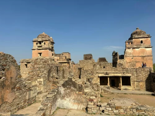 Rana Kumbha Palace ruins at Chittorgarh Fort in Rajasthan with pink sandstone towers, courtyards and walls under clear blue sky, perfect Rajasthan tour package.
