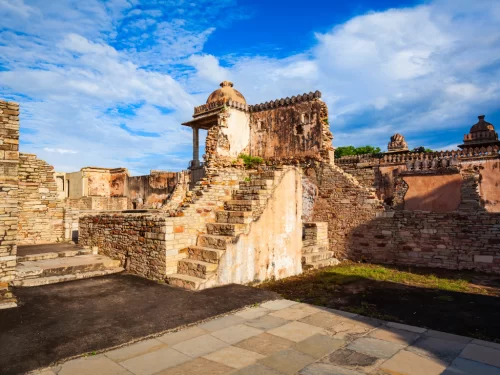 Side view of Rana Kumbha Palace ruins at Chittorgarh Fort in Rajasthan highlighting dome pavilion, stairs and weathered walls under partly cloudy sky, perfect Rajasthan tour package.