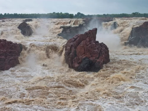 Raneh Falls near Khajuraho during monsoon season, featuring multiple cascades granite rocks Ken River mist forest backdrop, perfect Madhya Pradesh heritage nature tour package.
