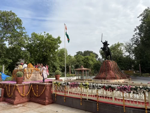 Rani Laxmibai Samadhi Sthal in Gwalior with decorated memorial platform, Indian flag, and equestrian statue of the queen, a historic landmark featured in Madhya Pradesh tour packages