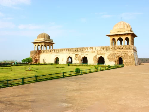 Rani Roopmati Pavilion at Gwalior Fort under clear skies, featuring domed pavilions and lush gardens, perfect heritage experience with Madhya Pradesh tour packages.