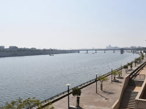Riverfront promenade at Sabarmati Riverfront Ahmedabad during daylight, featuring bridges and Sabarmati River, perfect romantic Gujarat tour package.