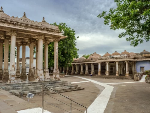 Pavilion complex at Sarkhej Roza Ahmedabad during cloudy day, featuring marble pillars and domes, perfect cultural Gujarat tour package.