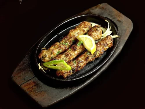 Seekh Kebabs are succulent minced meat skewers, spiced with aromatic herbs and grilled to smoky perfection, served sizzling with lemon and chutney.