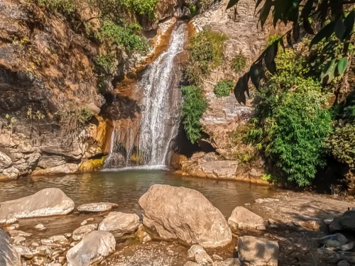 Shikhar Falls in Dehradun, Uttarakhand with water cascading over rocky cliffs into a natural pool, a serene stop included in Uttarakhand tour packages