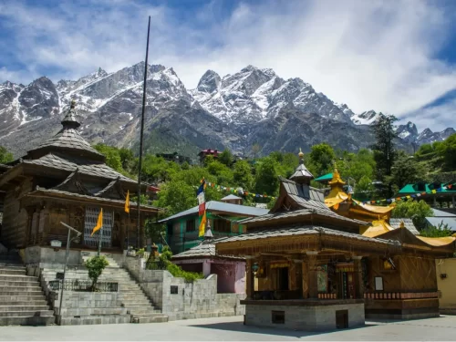 Shree Bering Nag Temple Chitkul Kinnaur, featuring wooden pagoda temples prayer flags steps colorful buildings backdrop snow peaks green valley, perfect Himachal Pradesh tour packages.