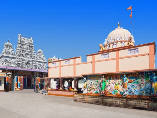 Annapurna Temple at Indore during clear daylight, featuring white gopurams saffron flag murals statues, perfect spiritual experience Madhya Pradesh tour package.