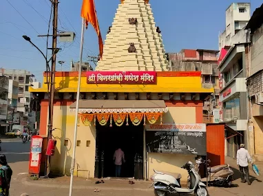 Entrance view of Shri Binkhambi Ganesh Mandir in Kolhapur, Maharashtra, featuring a tall temple shikhara and vibrant facade in a bustling city setting, a sacred stop included in Maharashtra tour packages.