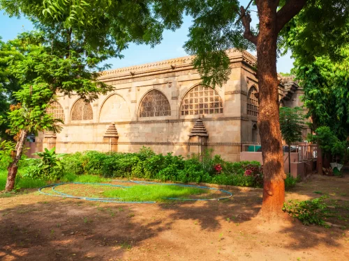 Sidi Bashir Mosque at Ahmedabad during daylight, featuring arched windows and palm trees, perfect cultural Gujarat tour package.