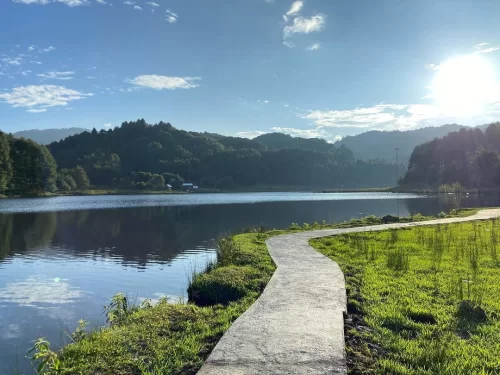 Siikhe Lake Chabo tranquil lakeside pathway with calm waters and scenic green hills in Arunachal Pradesh Tour Package.