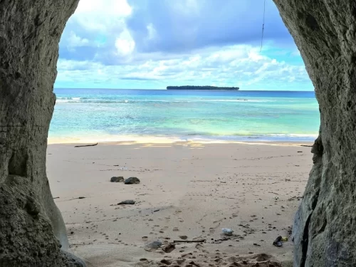 Cave view of Sitapur Beach in Neil Island at midday, featuring turquoise sea and distant island, perfect Andaman tour package
