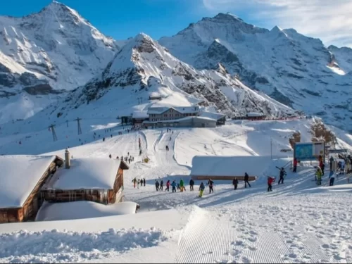 Skiers at Skiing Point Narkanda during winter sunny day, featuring snowy slopes, Himalayan peaks, cable car, chalets, perfect adventure Himachal Pradesh tour package.