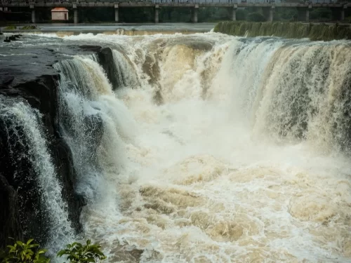 Powerful Someshwar Waterfall in Nashik Maharashtra with wide cascading waters and bridge visible above the rocky riverbed
