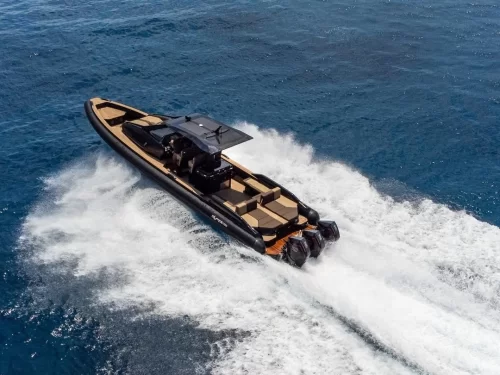 Speed boating activity with a luxury motorboat cruising at high speed across the open sea, creating powerful white waves and water spray behind it.