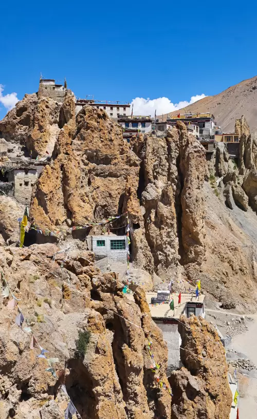 Spiti Valley Tour Package Himachal featuring ancient cliffside monastery perched on rugged mountains under clear blue sky.