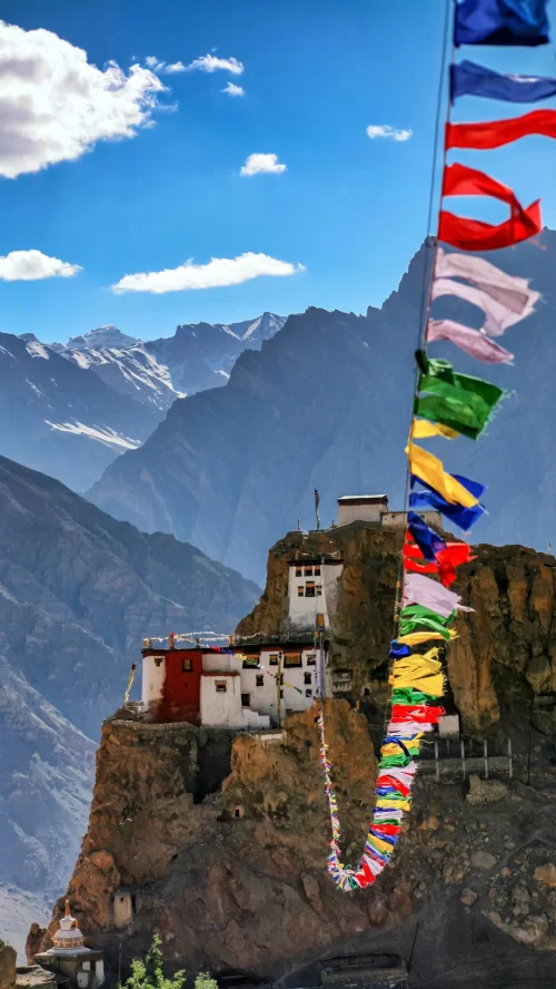 Spiti Valley cliffside monastery with prayer flags featured in Himachal Pradesh tour packages