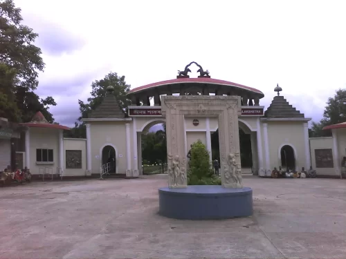 Grand entrance gate at Srimanta Sankardev Kalakshetra Guwahati during cloudy day, featuring Assamese architecture statues trees, perfect cultural experience Assam tour package.
