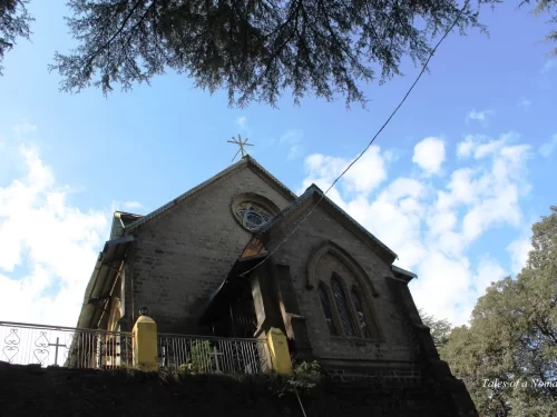 St. Francis Church in Dalhousie featuring a historic stone building with arched windows, circular stained-glass detail, and a cross on the roof set against a blue sky and surrounding trees.