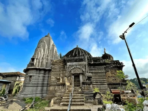 Historic stone architecture of Sundar Narayan Mandir in Nashik, Maharashtra, featuring detailed carvings and a tall shikhara against a blue sky, a revered temple included in Maharashtra tour packages. 