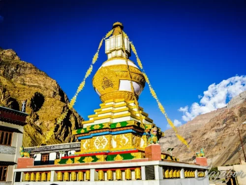 Golden stupa Tabo Monastery Spiti Valley Himachal Pradesh clear skies, featuring towering gilded chorten prayer flags rocky mountains traditional buildings, ideal heritage adventure Himachal tour package.