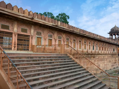 Taj-ul-Masajid walls at Bhopal during clear daylight, featuring red sandstone arches dome stairs trees, perfect cultural Madhya Pradesh tour package.