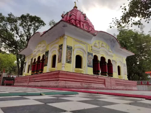 Tarna Devi Temple Mandi yellow white red curved roof Bengali style facade deity wall paintings red pillars checkered floor green trees cloudy sky, perfect Shyama Kali Shakti Peeth hilltop shrine, Himachal Pradesh tour packages.