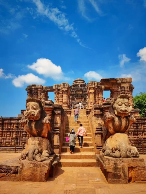 Visitors walking up carved stone steps of Konark Sun Temple in Odisha with majestic lion sculptures featured in Odisha tour packages