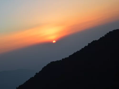 Sunrise at Tiger Hill in Darjeeling, featuring glowing sky over dark mountain silhouettes, perfect sunrise Sikkim tour package