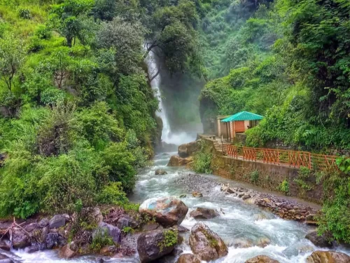 Tiger Falls in Chakrata, Uttarakhand cascading through lush green hills into a rocky stream, a scenic nature spot included in Uttarakhand tour packages