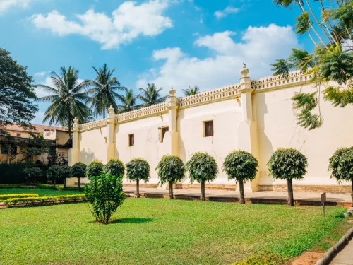 Tipu Sultan Summer Palace Bangalore sunny day, white walls pillars palms trees garden lawn, perfect Karnataka tour package.