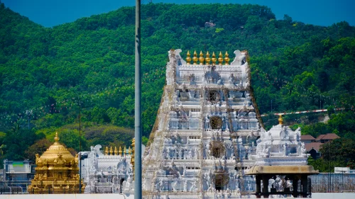 Tower view at Tirumala Venkateswara Temple Tirupati during clear day, featuring green hills and golden kalasa, perfect spiritual experience Tirupati tour package.
