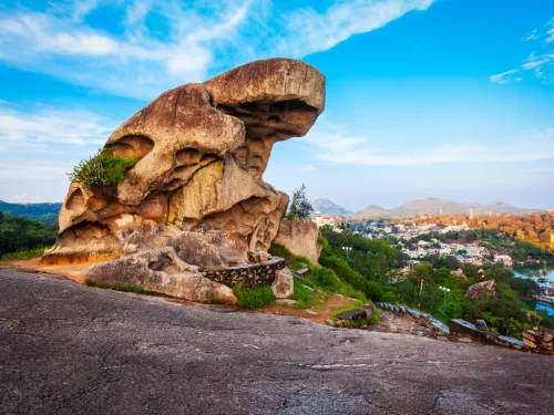 Toad Rock Sunset Point Mount Abu Rajasthan, iconic toad-shaped rock formation overlooking Nakki Lake town hills lush greenery blue skies, perfect Rajasthan hill station tour packages.