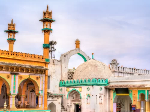 Hazrat Nizamuddin Dargah housing tomb of Sufi saint Nizamuddin Auliya Delhi during overcast day, featuring green turquoise minarets white dome yellow orange arches intricate Islamic architecture, perfect spiritual heritage experience with Nizamuddin Darga