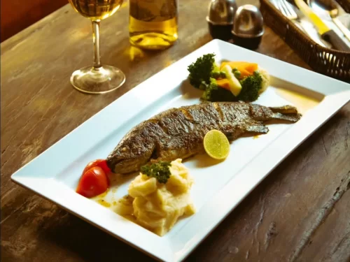 Trout Fish is a delicately grilled freshwater delight, served with a squeeze of lemon and fresh vegetables for a wholesome, flavorful experience.
