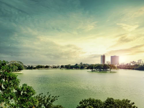 Ulsoor Lake Bangalore golden hour, serene lake trees island highrises skyline, perfect Karnataka tour package.
