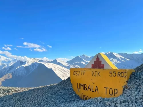 Umba La Pass Umbala Top Ladakh yellow army signboard 062 TF VJK 55 RCC snowy Himalayan peaks blue sky clouds gravel foreground; rugged Kargil Drass Suru adventure photography package.