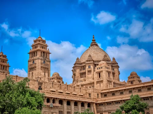 Umaid Bhawan Palace at Jodhpur during sunny day, featuring golden domes, minarets, Art Deco architecture, perfect romantic experience Rajasthan tour packages.