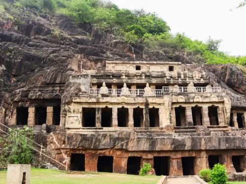 Undavalli Caves at Vijayawada during clear weather, featuring rock-cut facade and green hills, perfect cultural experience Andhra Pradesh tour package.