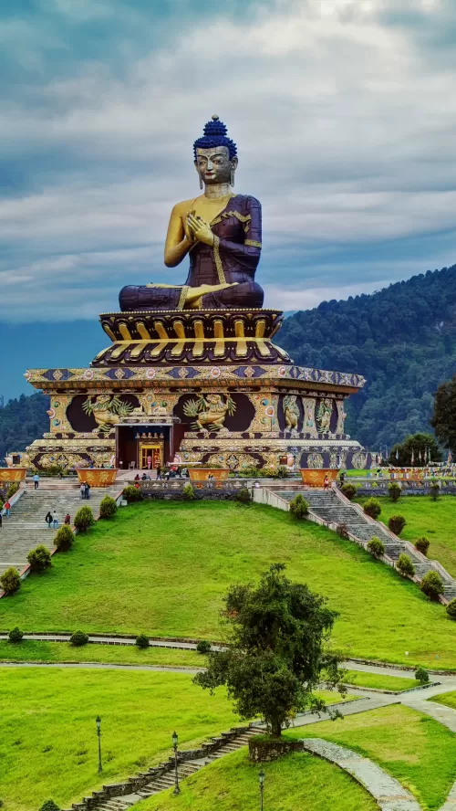 Magnificent Buddha statue at Buddha Park in Ravangla surrounded by lush green hills, a serene spiritual attraction featured in Sikkim tour packages.