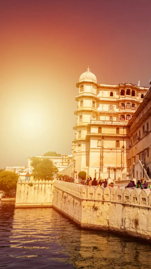 City Palace in Udaipur Rajasthan overlooking Lake Pichola with grand royal architecture glowing at sunset included in Rajasthan tour packages