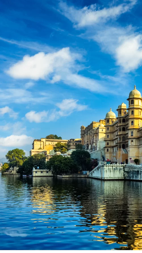 City Palace Udaipur Rajasthan at lakeside during clear day, featuring Lake Pichola reflections, perfect romantic experience Rajasthan tour package