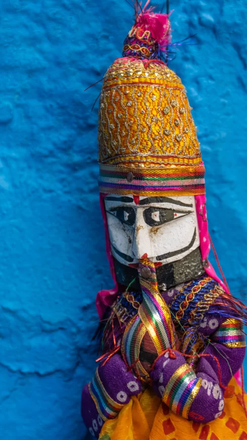 Rajasthani puppet art in Jodhpur Rajasthan against blue wall, featuring colorful attire, perfect cultural experience Rajasthan tour package
