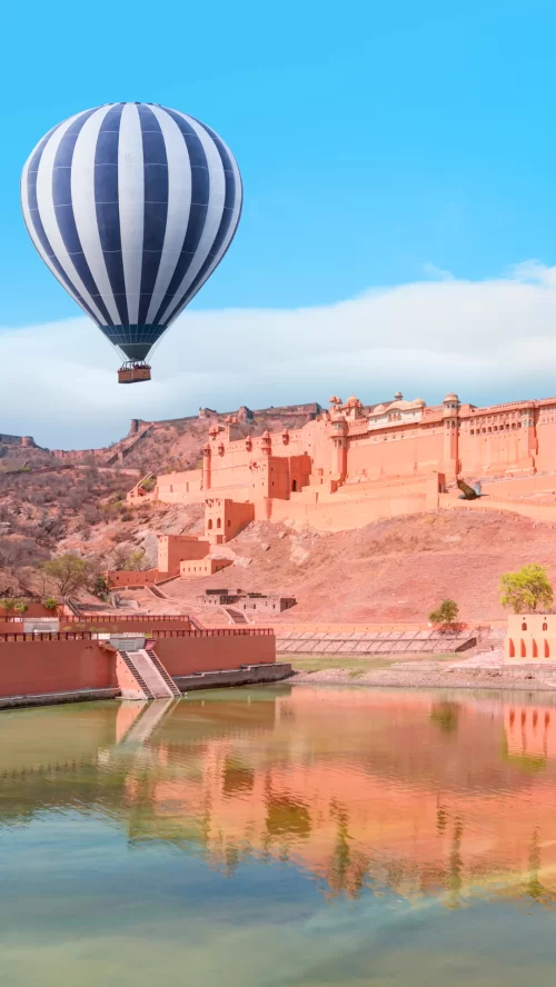 Hot air balloon over Amber Fort in Jaipur Rajasthan with palace reflection in Maota Lake featured in Rajasthan tour packages