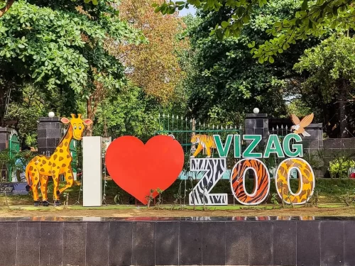 I love Vizag Zoo entrance sign at Indira Gandhi Zoological Park during sunny day, featuring giraffe tiger animals trees, perfect family Andhra Pradesh tour package.