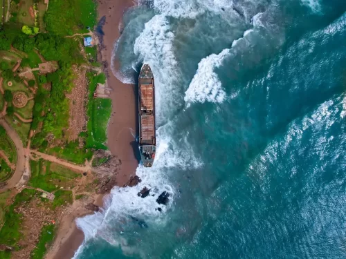 Aerial view of MV Maa shipwreck at Tenneti Park beach Vizag, featuring waves park greenery rocks, perfect coastal Andhra Pradesh tour package.